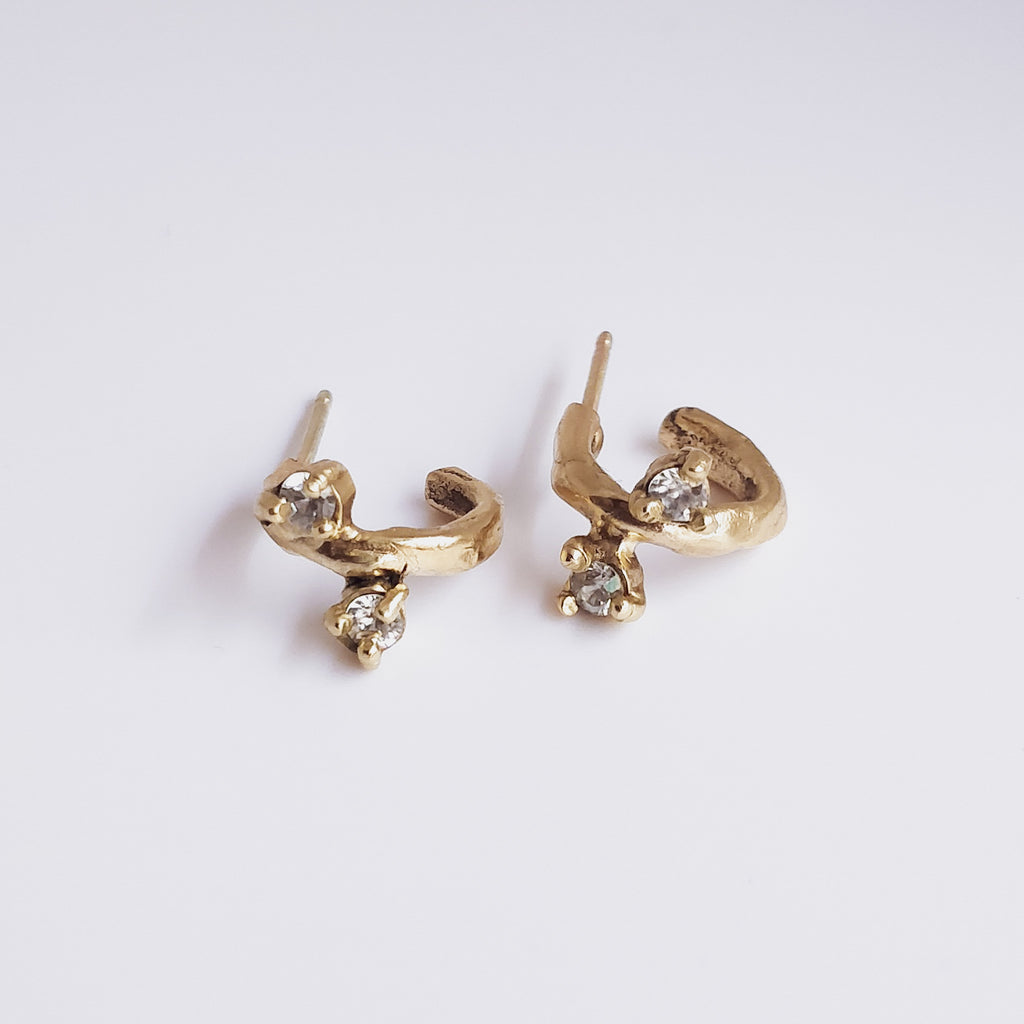 9k yellow gold small huggie hoop earrings with white lab sapphires on a white background